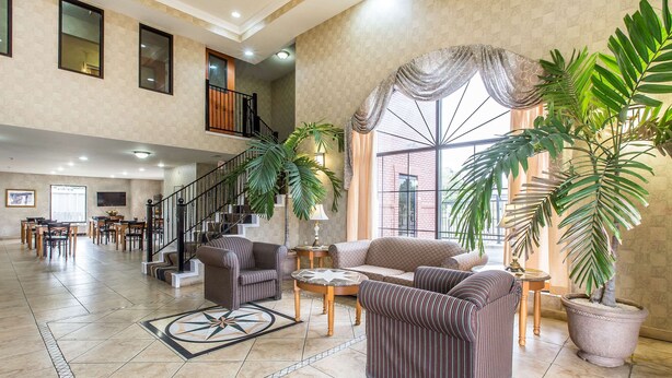 A spacious living area with a staircase, multiple seating options, and large windows.