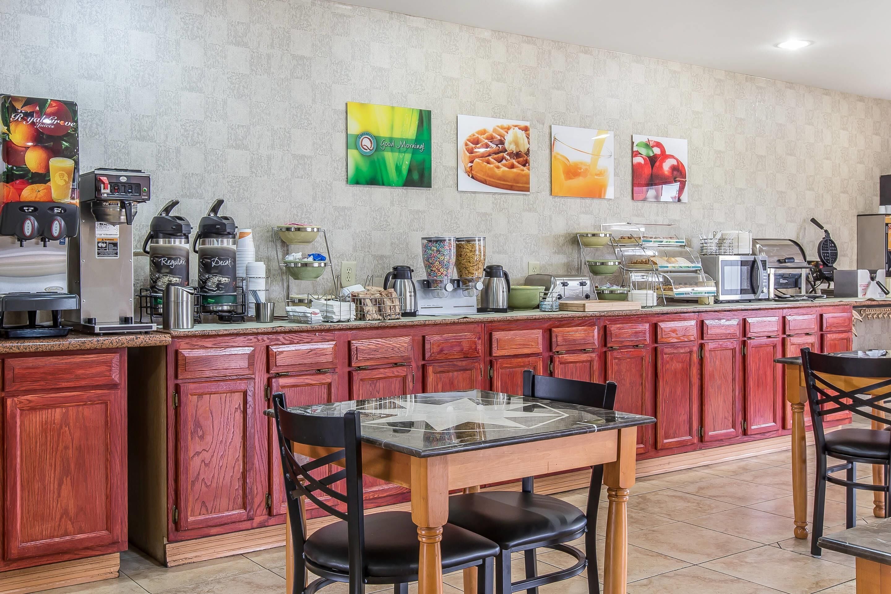 A breakfast bar with coffee machines, a microwave, and a fruit display.