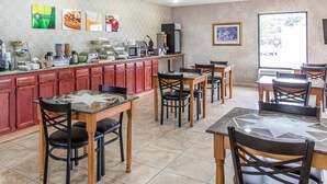 A restaurant with a counter, multiple tables, and chairs.