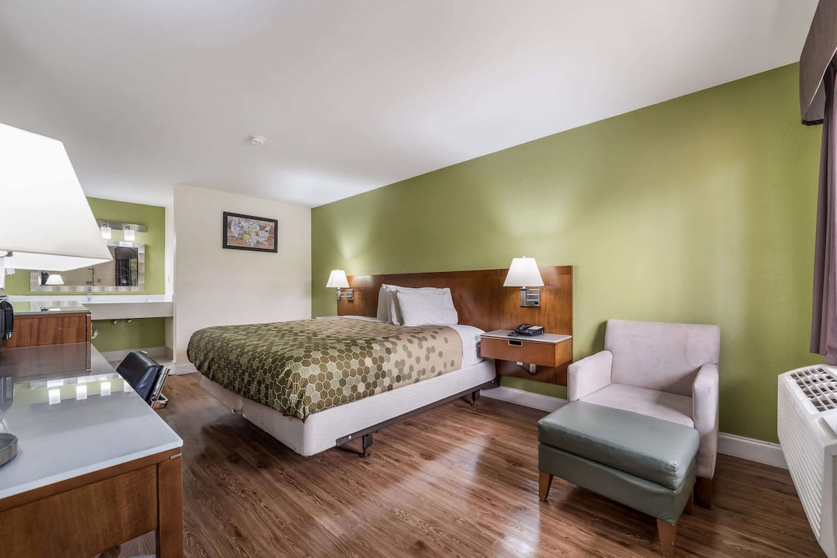 Een hotelkamer met een bed, nachtkastjes, een bureau, een stoel en een radiator.