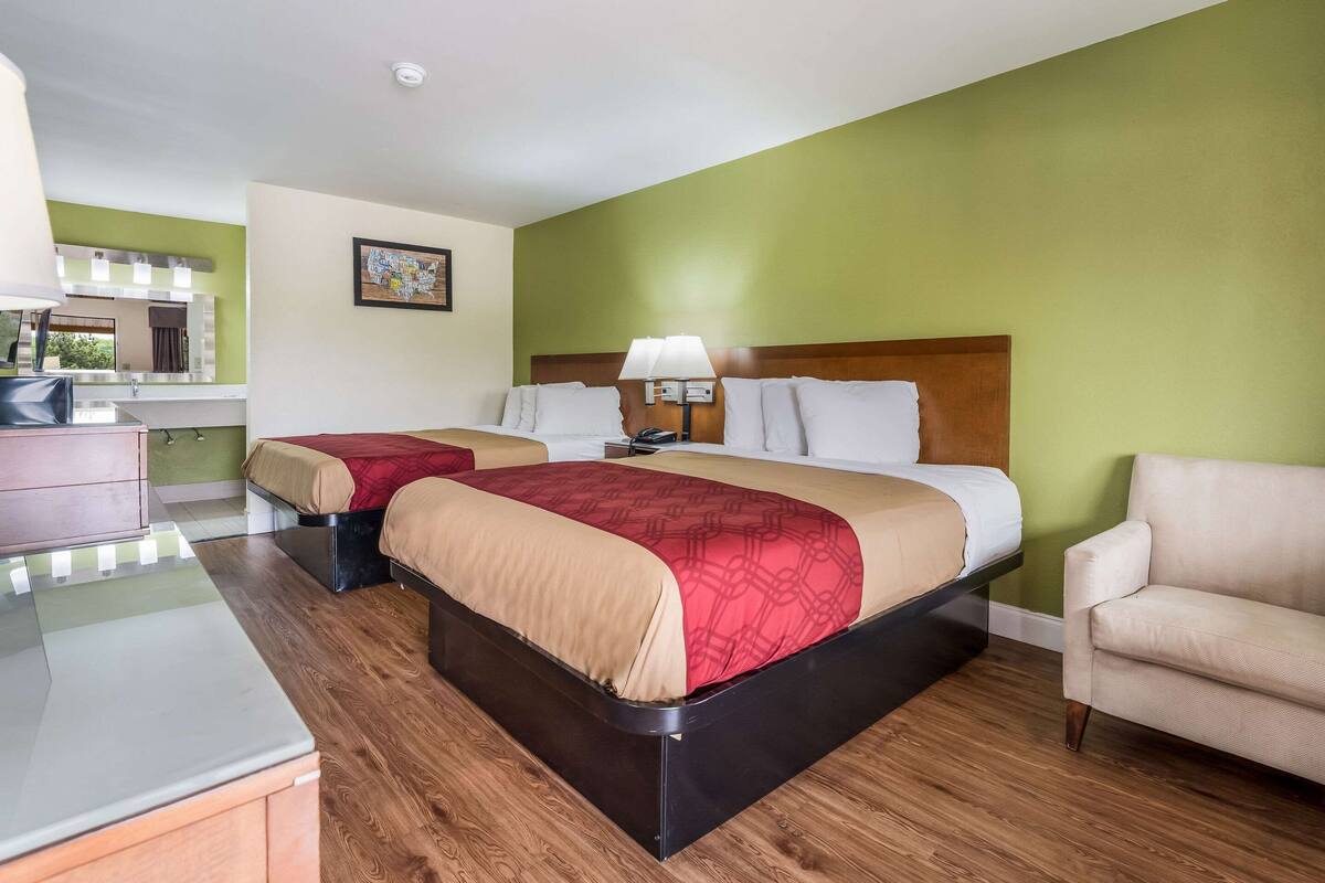 Een hotelkamer met twee bedden, een bureau en een stoel.