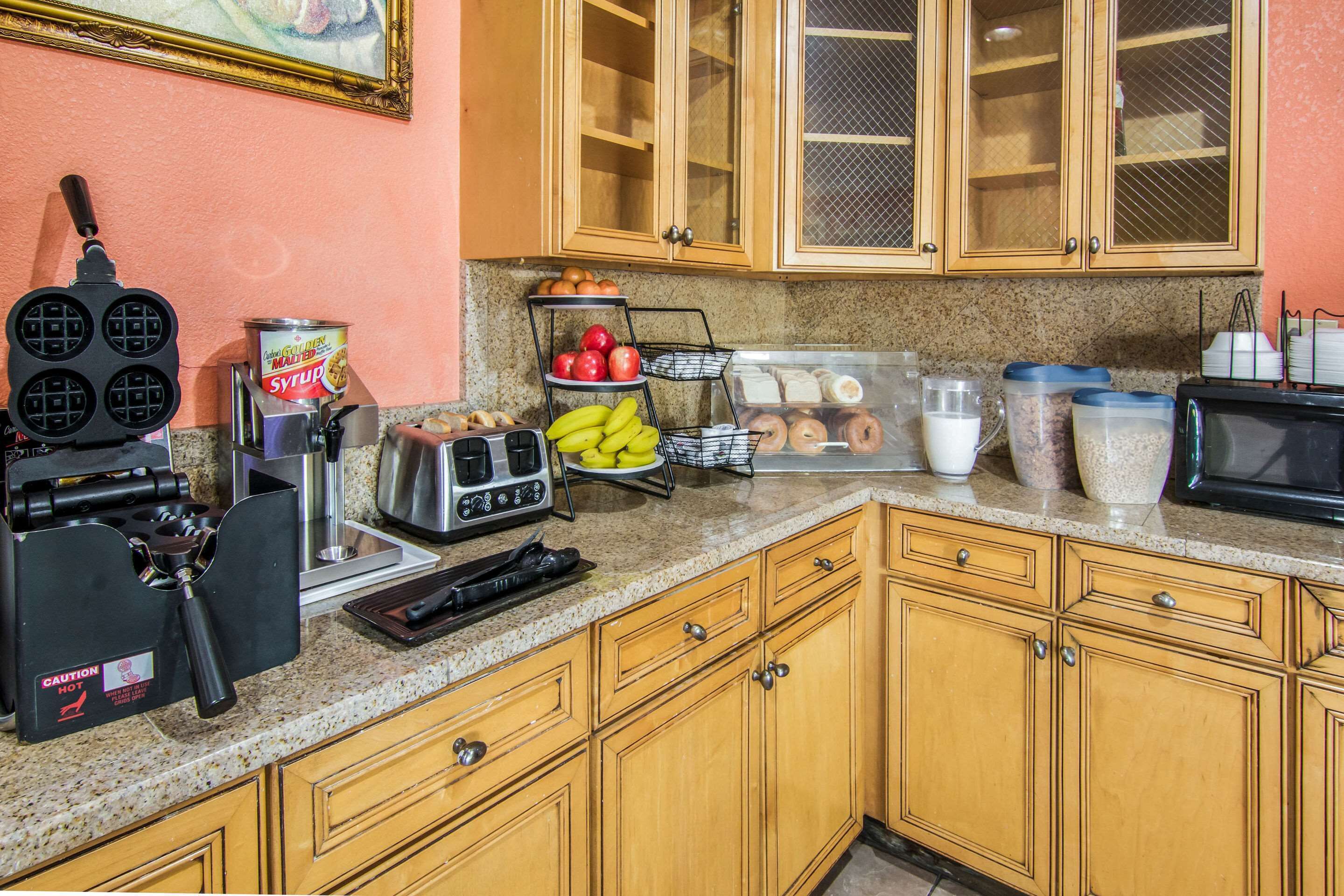 Una cocina con una máquina para hacer gofres, una tostadora y diversos alimentos sobre la encimera.