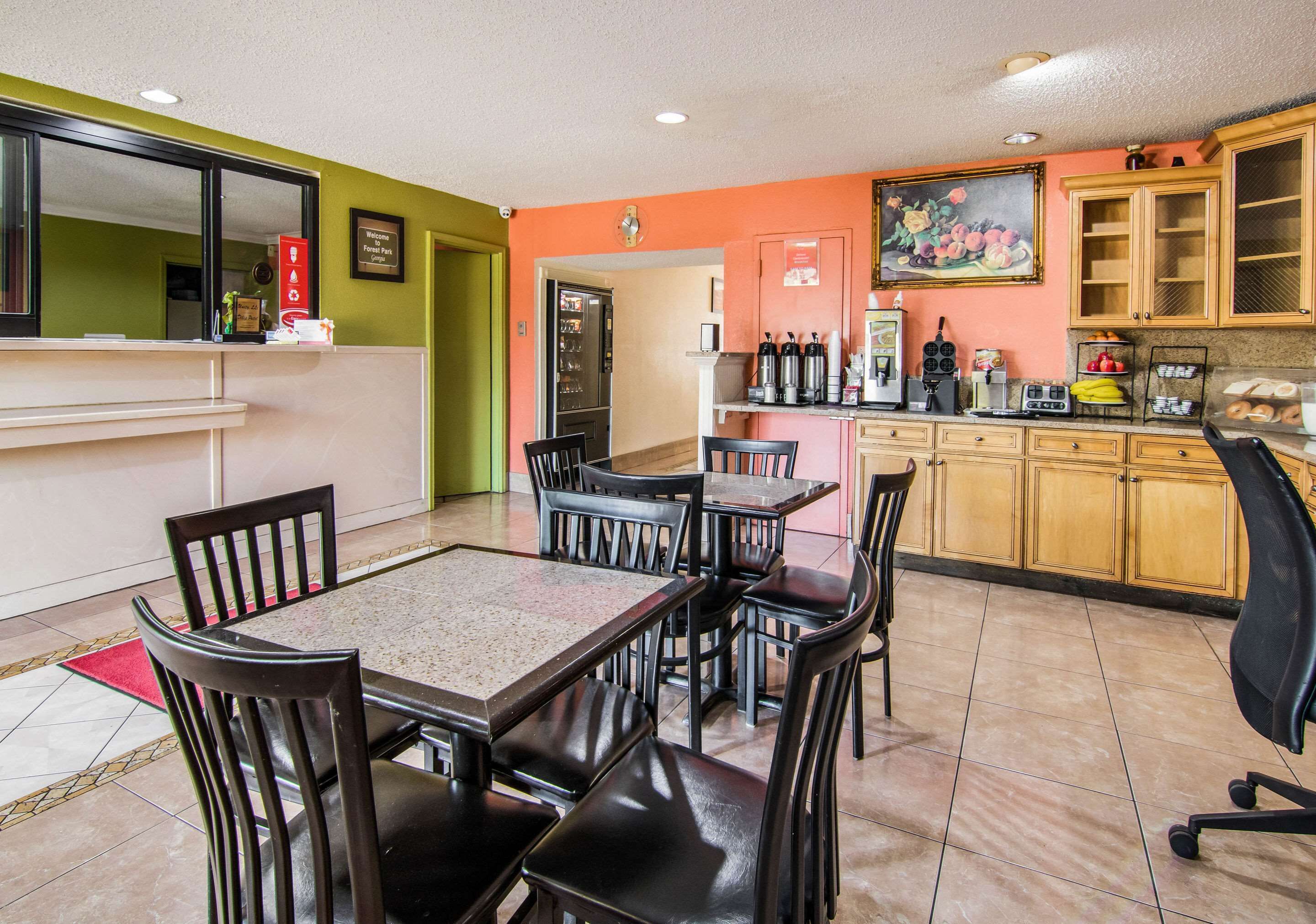 A dining area with a table and chairs, a kitchen with cabinets and appliances, and a reception desk.