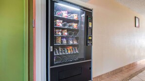 A vending machine with snacks and drinks in a hallway.