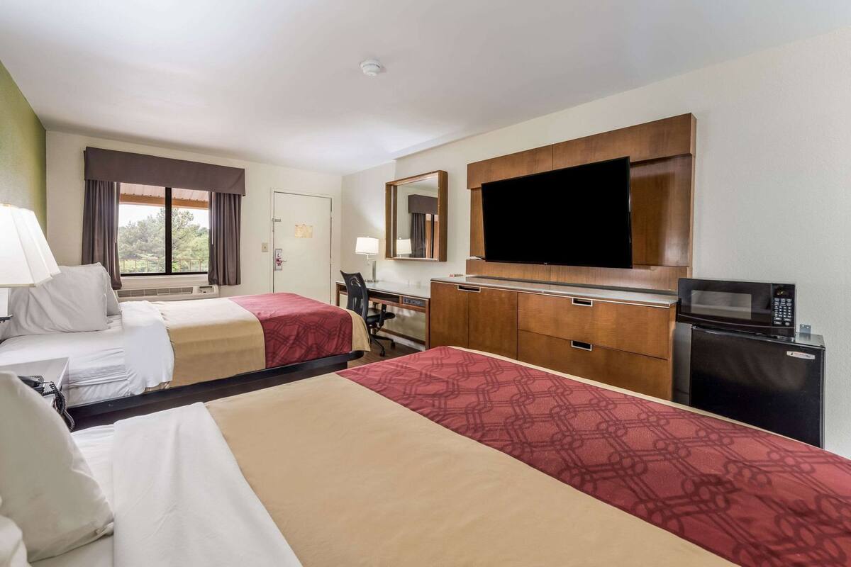 Een hotelkamer met twee bedden, een bureau, een televisie en een magnetron.