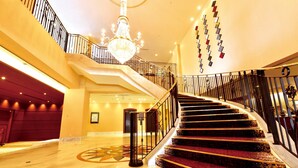 A grand staircase with a chandelier, a red carpet, and a wall with hanging nameplates. - Crowne Plaza ANA Nagasaki Gloverhill by IHG (Nagasaki)