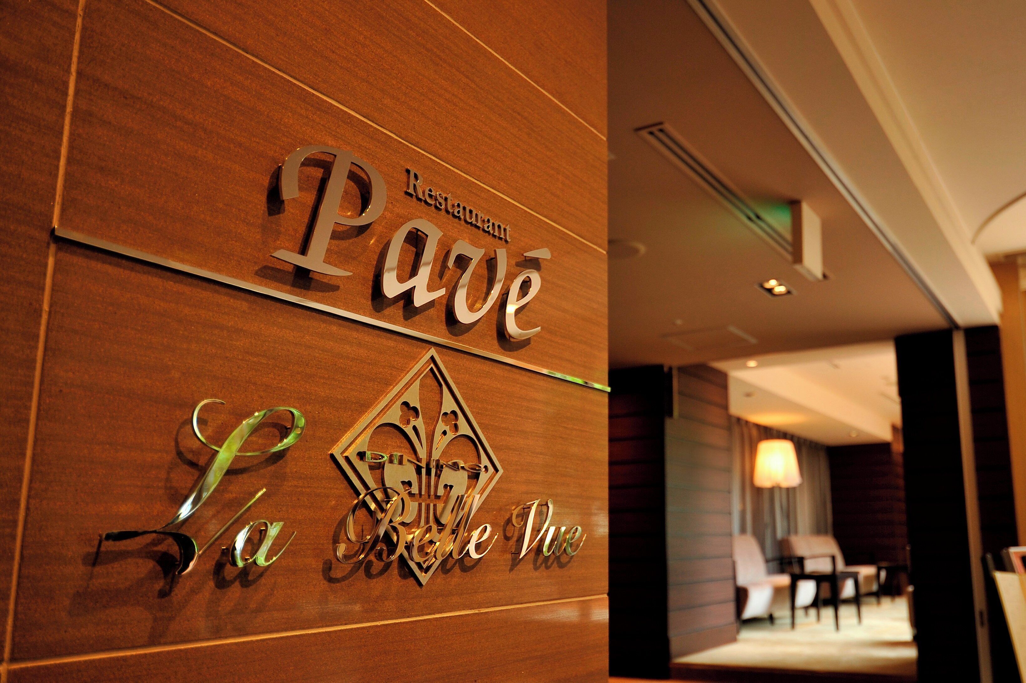 A hotel sign with the name 'La Belle Vue' and a decorative emblem.