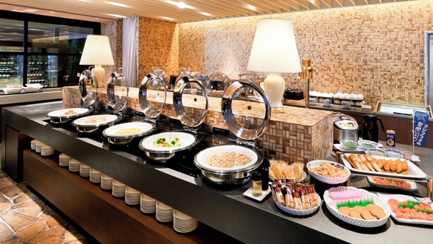 A buffet with various food items and a brick wall background. - Crowne Plaza ANA Nagasaki Gloverhill by IHG (Nagasaki)