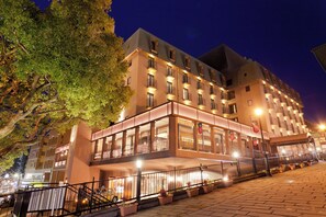 A multi-story hotel with a ground-level restaurant and a balcony with a railing.