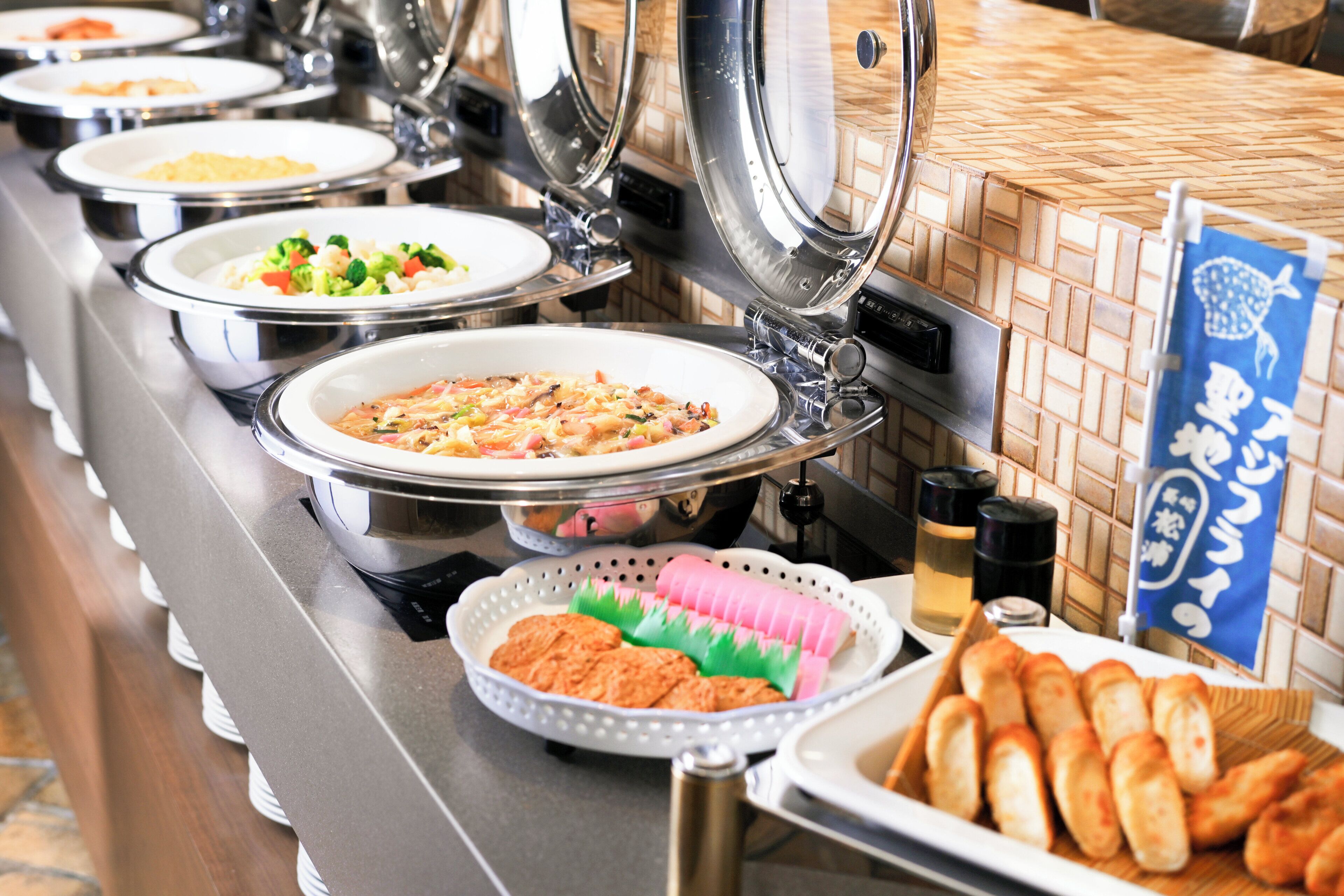 A buffet with various dishes, including pasta, salads, and bread.