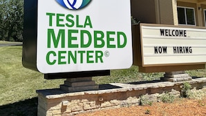 A sign for the Tesla Medbed Center with a DNA helix logo.