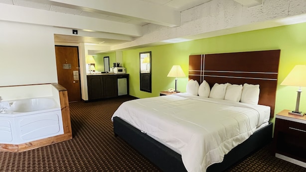 A hotel room with a large bed, a desk, a chair, and a bathroom.