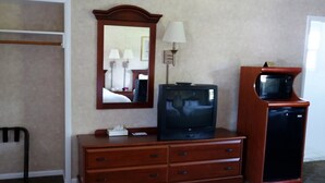 A hotel room with a wooden dresser, a television, a microwave, and a mirror. - Monument Mountain Motel (Great Barrington)