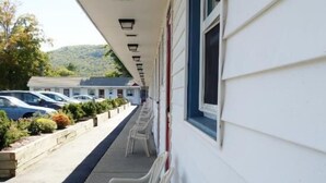 A row of white plastic chairs on a covered outdoor area with a white building in the background. - Monument Mountain Motel (Great Barrington)