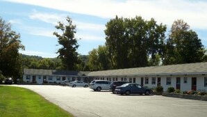 A motel with a parking lot and several cars parked. - Monument Mountain Motel (Great Barrington)