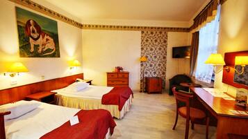 A hotel room with two beds, a desk, a chair, a dresser, and a painting on the wall.