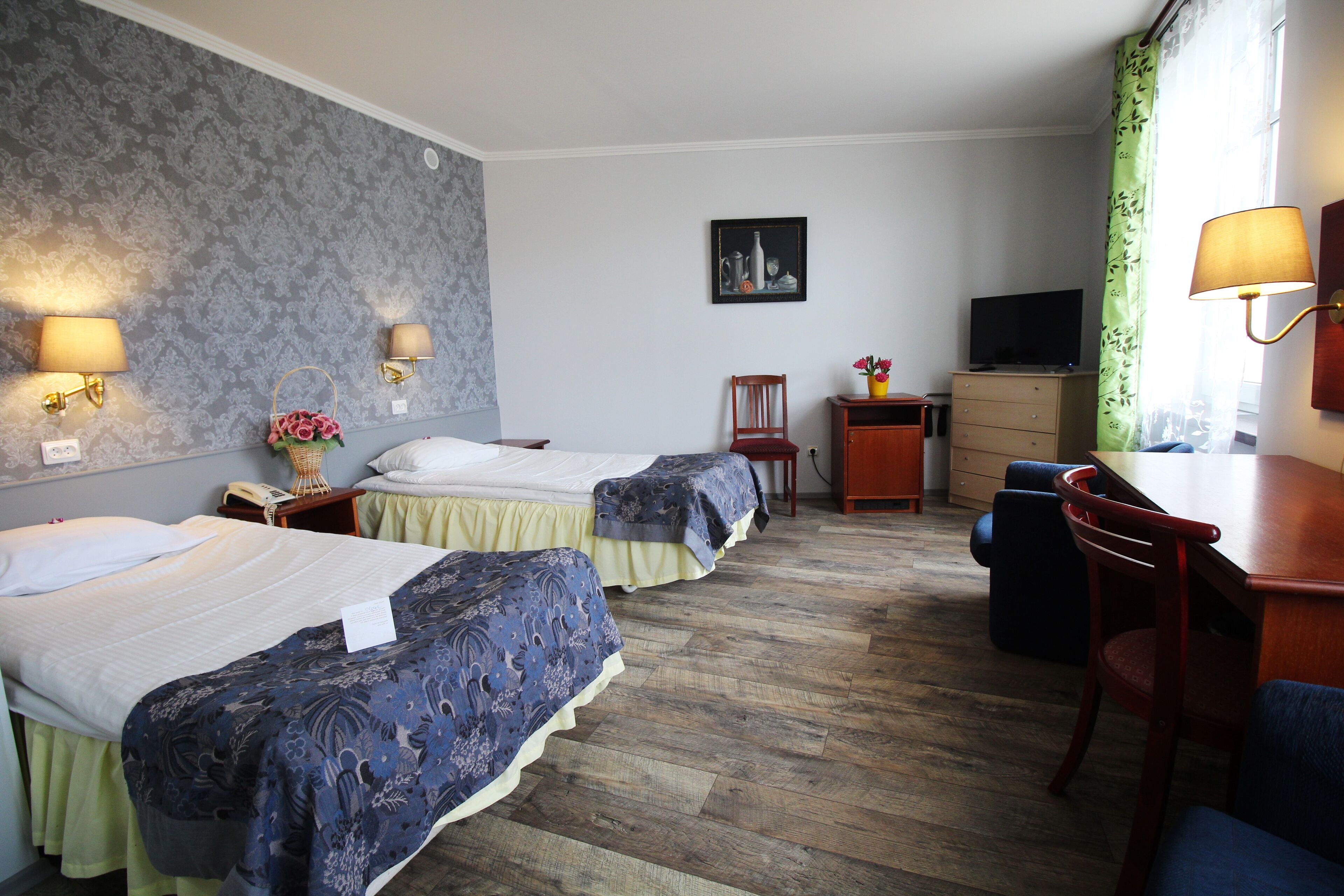 Ein Hotelzimmer mit zwei Betten, einem Schreibtisch, einem Sessel, einem Fernseher und einer Lampe.