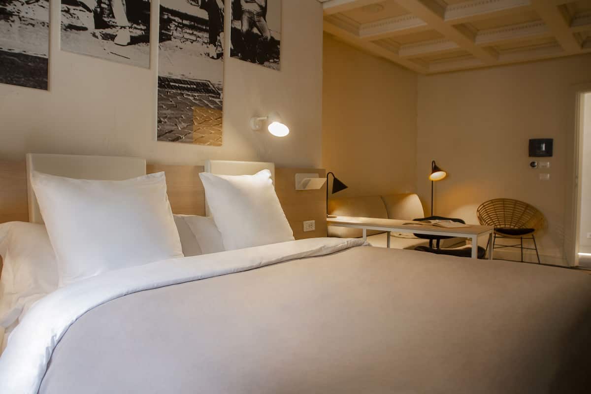 Une chambre d’hôtel avec un grand lit, un bureau, une chaise et des œuvres d’art murales.