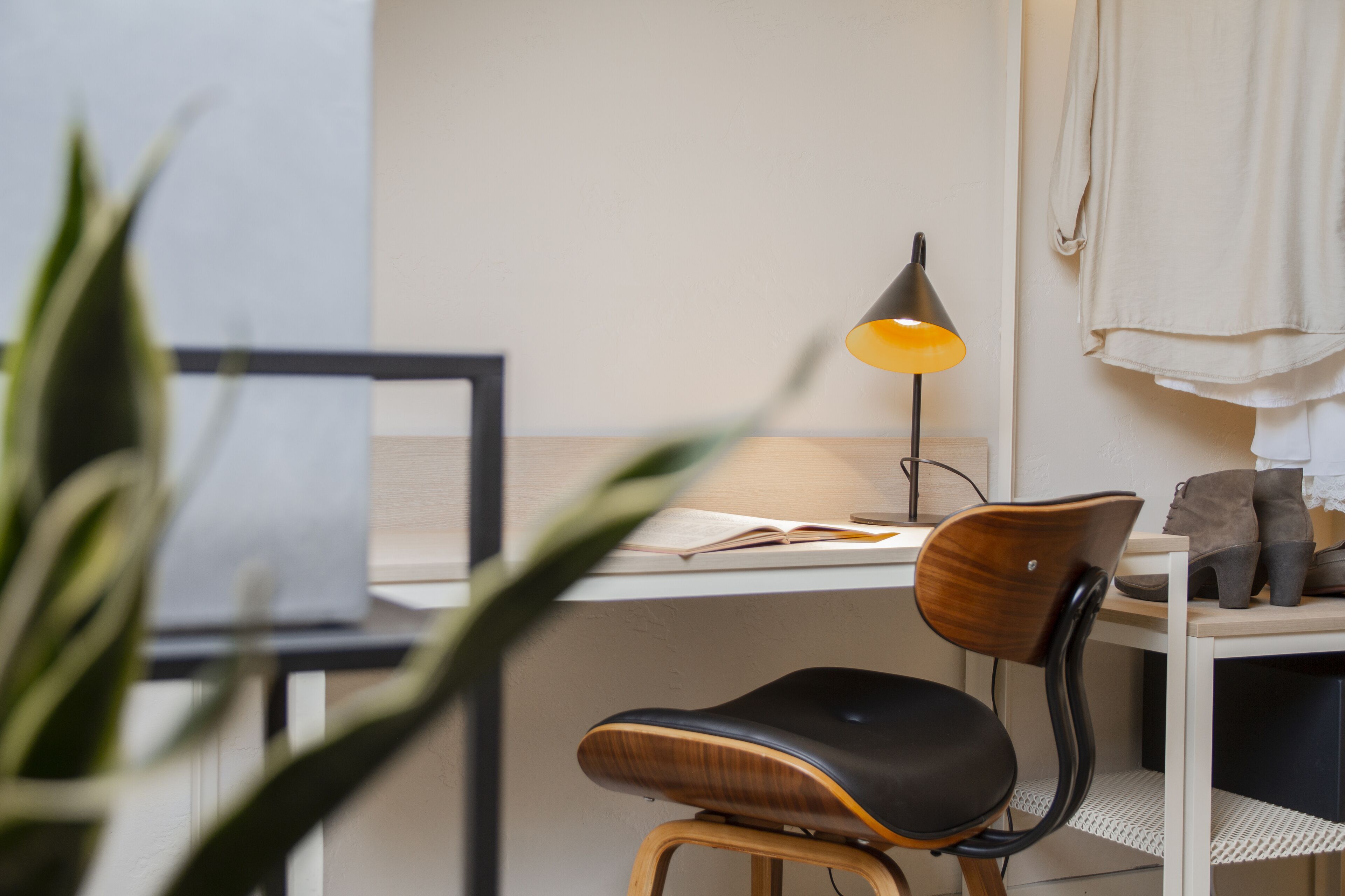 A workspace with a desk, chair, lamp, and a plant.