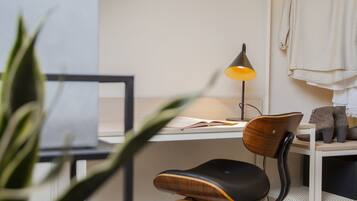 A workspace with a desk, chair, lamp, and a plant.