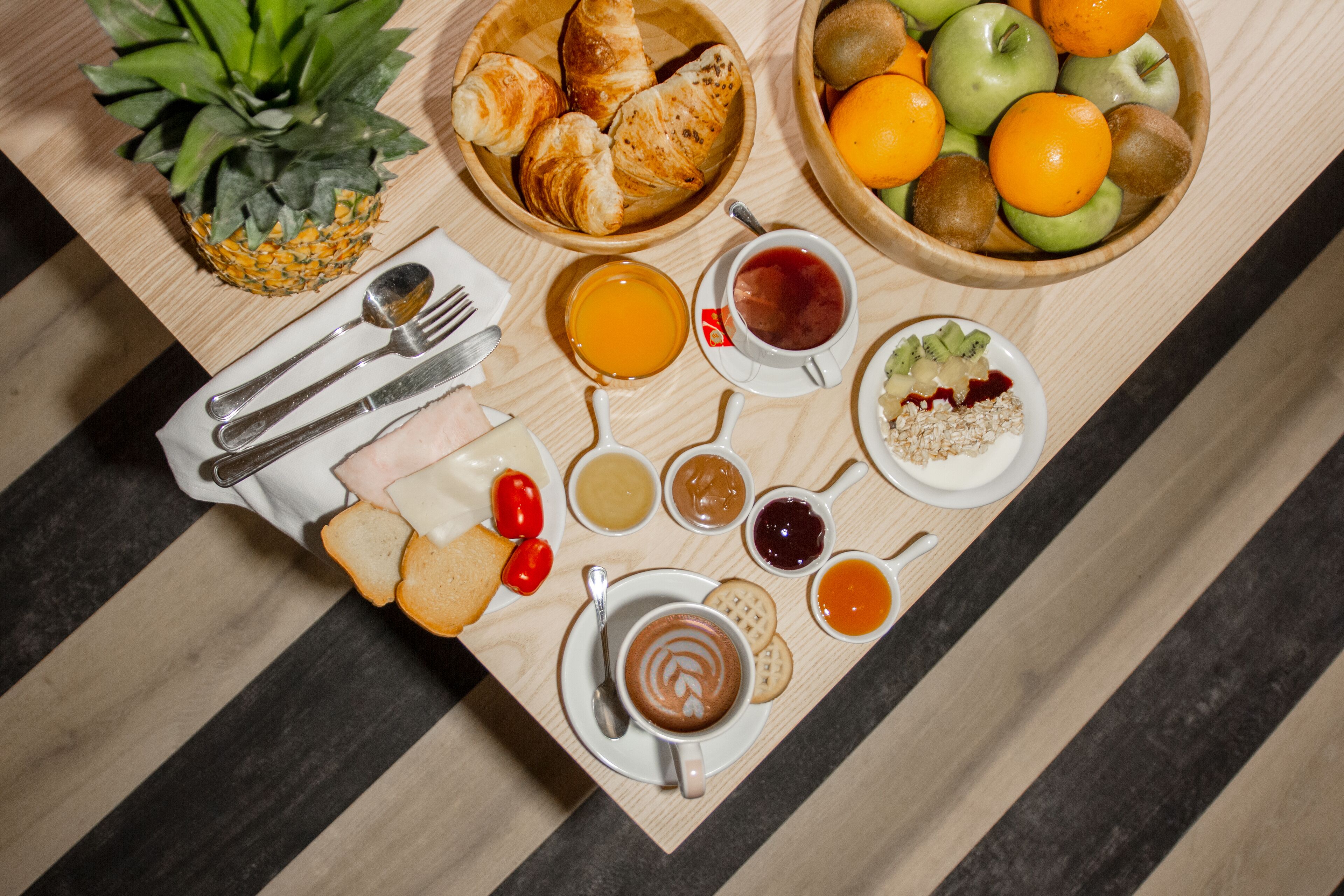 Ein Frühstücksbuffet mit Croissants, Früchten und verschiedenen Aufstrichen.