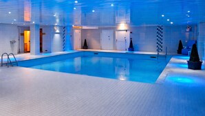 An indoor swimming pool with tiled flooring, a ladder, and a door leading to another room. - The Old Mill Hotel (Bury)