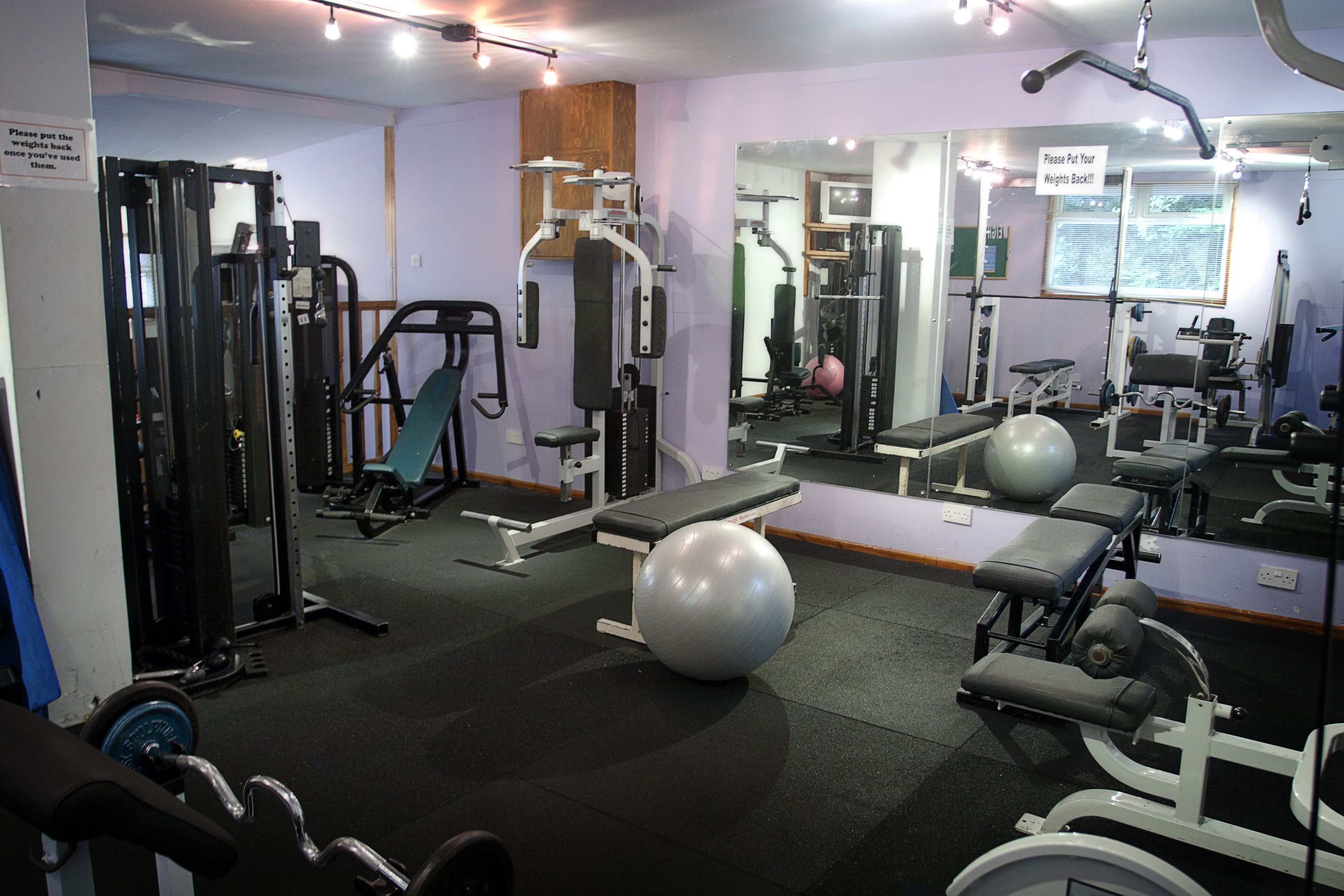 A gym with various exercise equipment, a bench, and exercise balls.