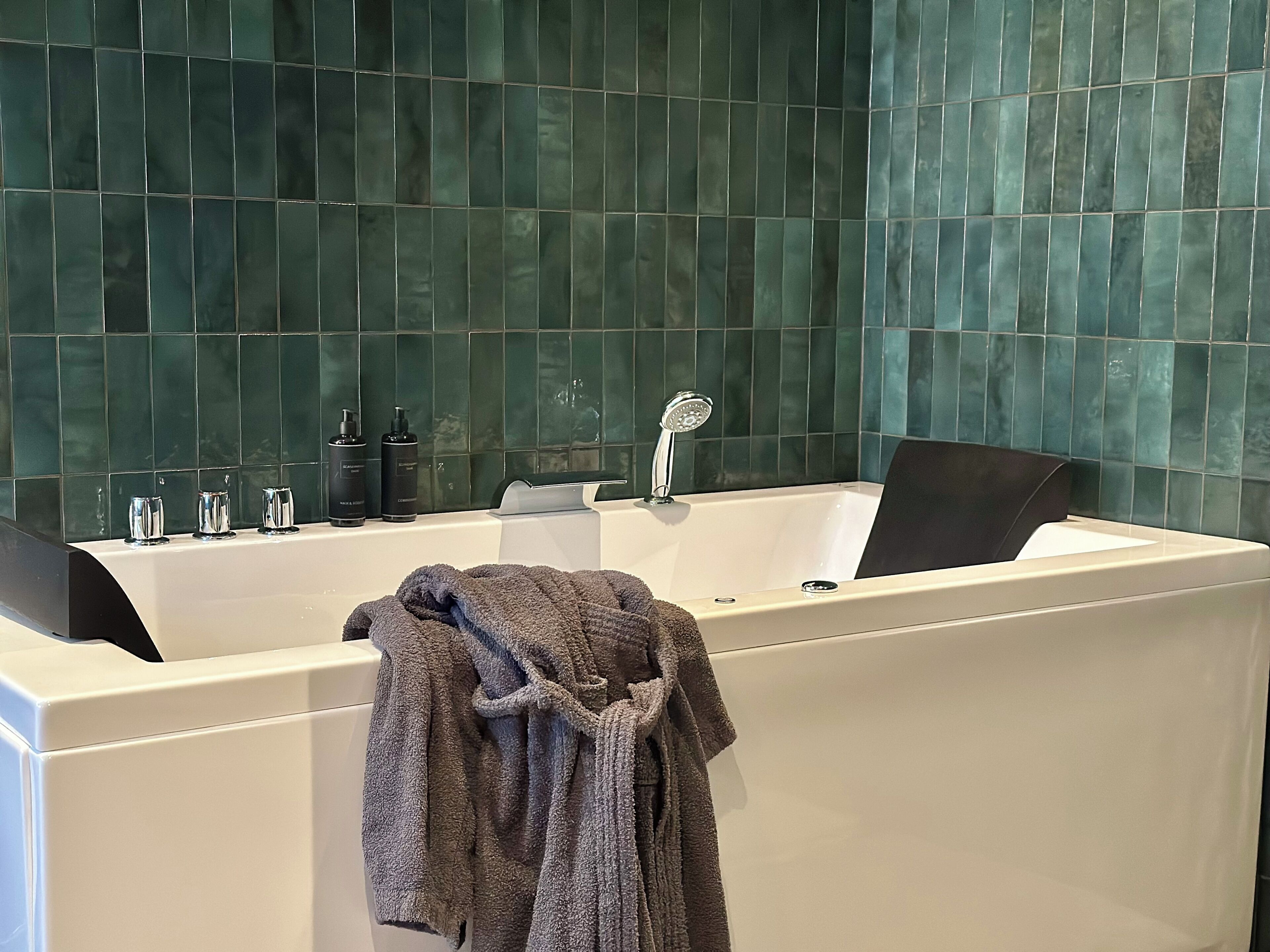 Une salle de bain moderne avec une grande baignoire, un porte-serviettes et des articles de toilette disposés sur le bord.