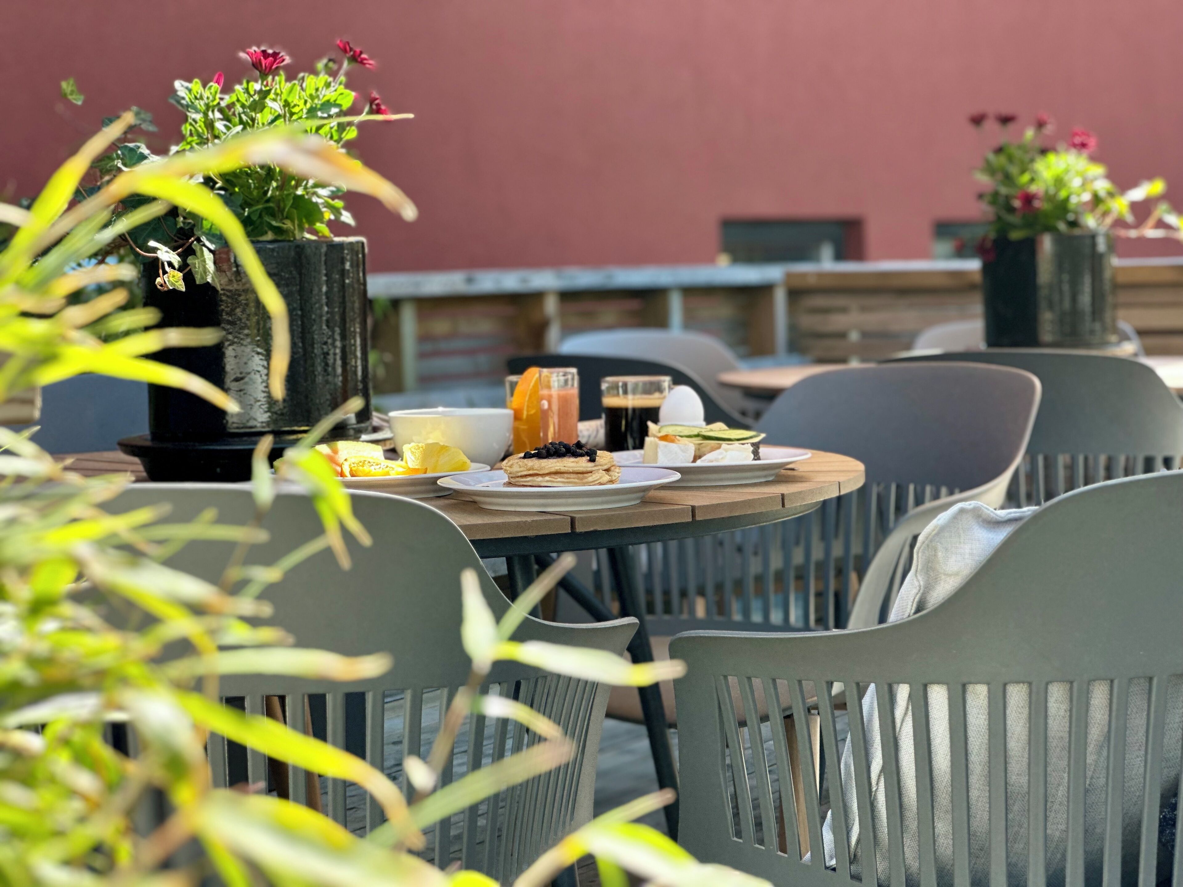 An outdoor dining area with a round table, chairs, and a variety of food and drinks.