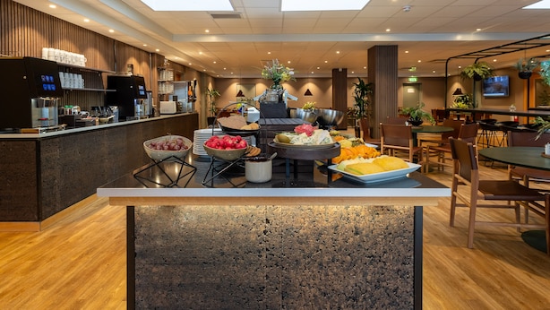 A modern hotel lobby with a reception desk, seating area, and a buffet setup. - Spar Hotel Gårda (Gothenburg)