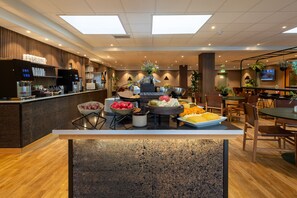A modern hotel lobby with a reception desk, seating area, and a buffet setup. - Spar Hotel Gårda (Gothenburg)