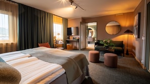 A modern hotel room with a large bed, a desk, a sofa, and a round mirror. - Spar Hotel Gårda (Gothenburg)