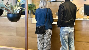 Uma área de recepção com um balcão de madeira, um relógio e plantas penduradas.