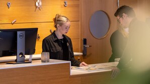 A reception desk with a computer monitor, a glass, and a map. - Spar Hotel Gårda (Gothenburg)