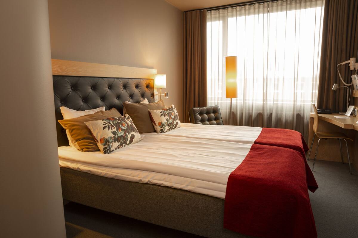 Habitació d'hotel amb un llit gran, dues taules de nit, un escriptori i una cadira.