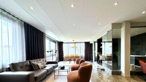 A modern living room with a sofa, armchair, and dining area.