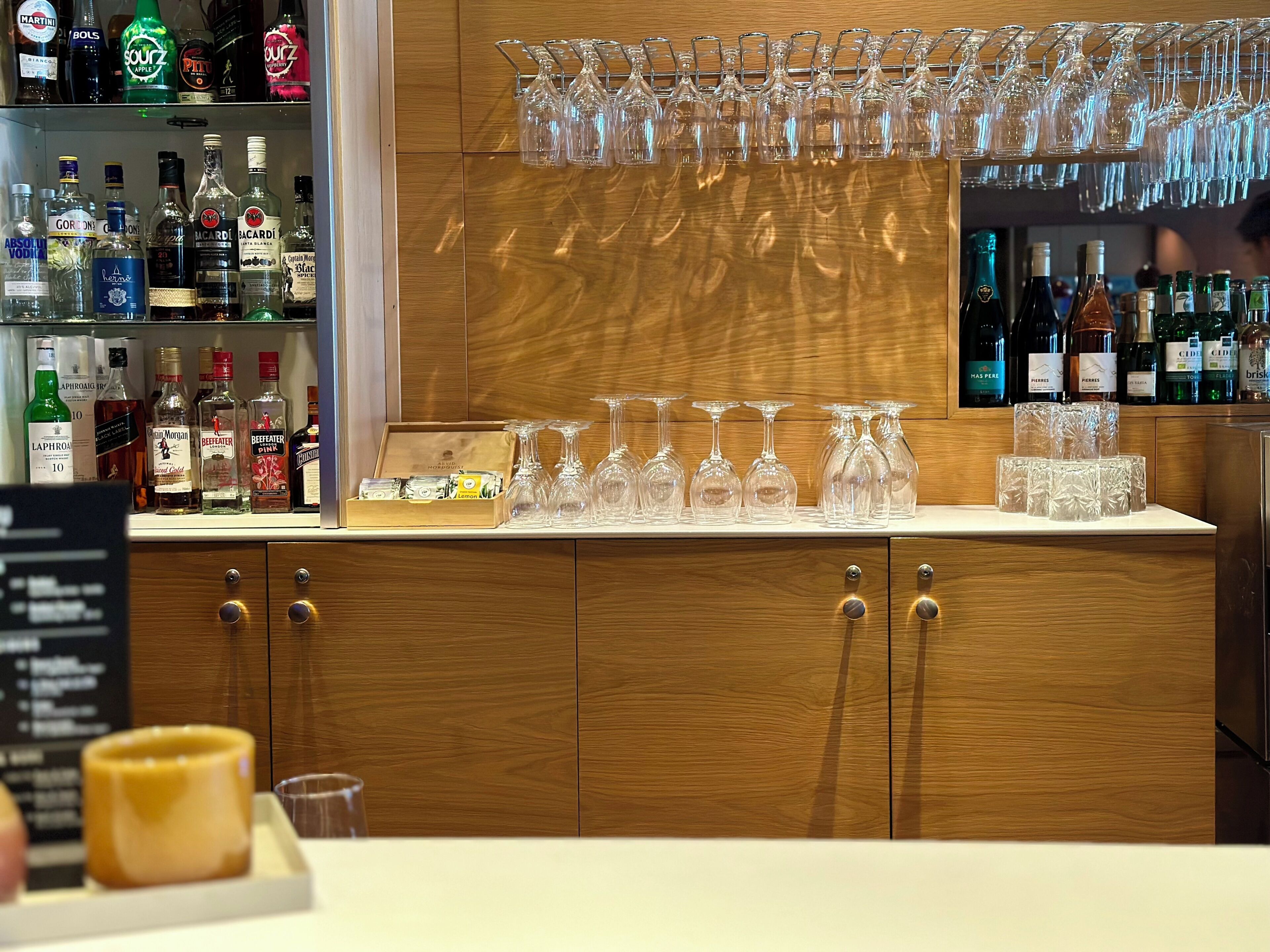 A bar area with a variety of liquor bottles, a selection of wine glasses, and a wooden cabinet.