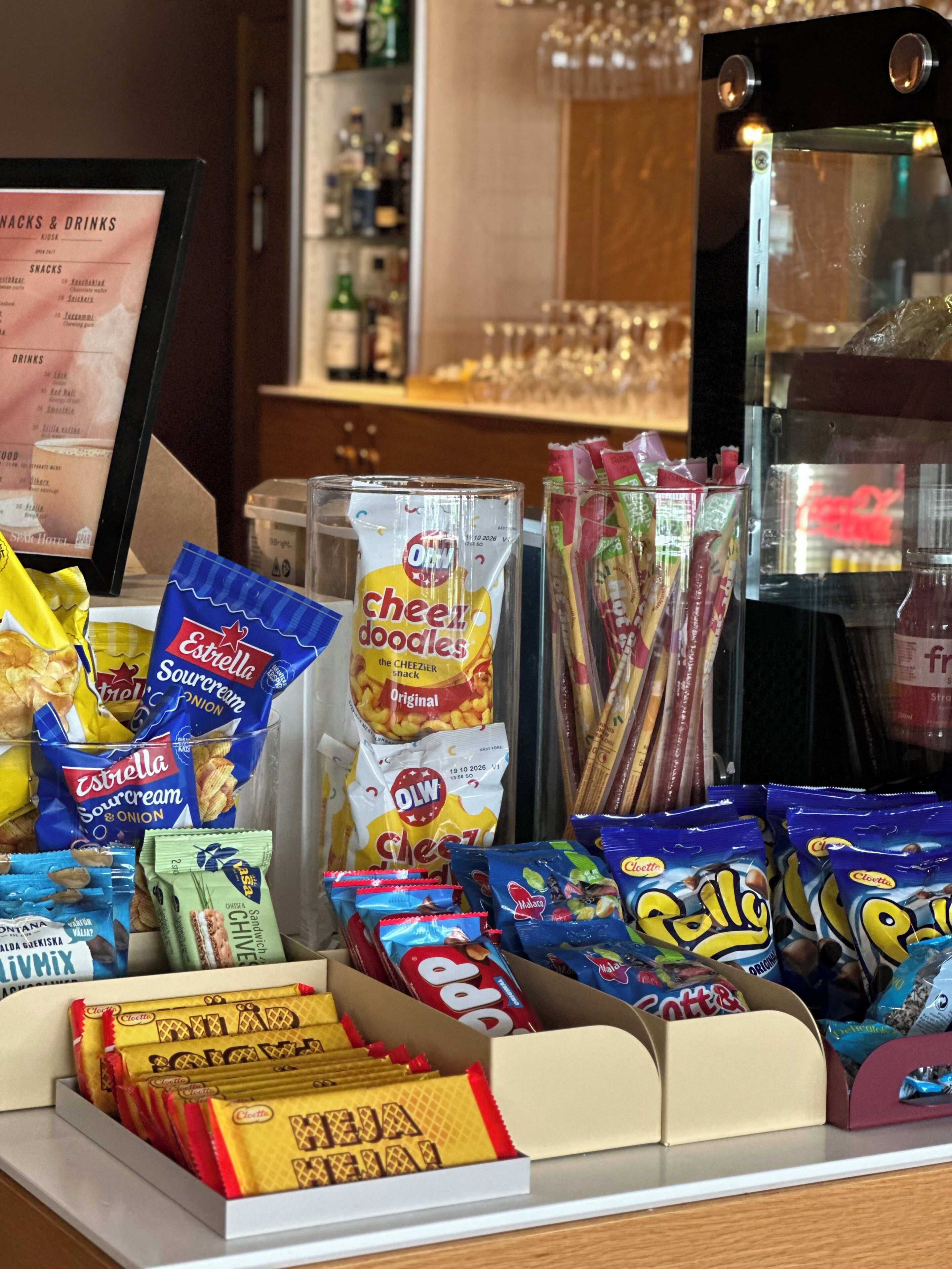 A snack display with various packaged foods and a menu board in the background.
