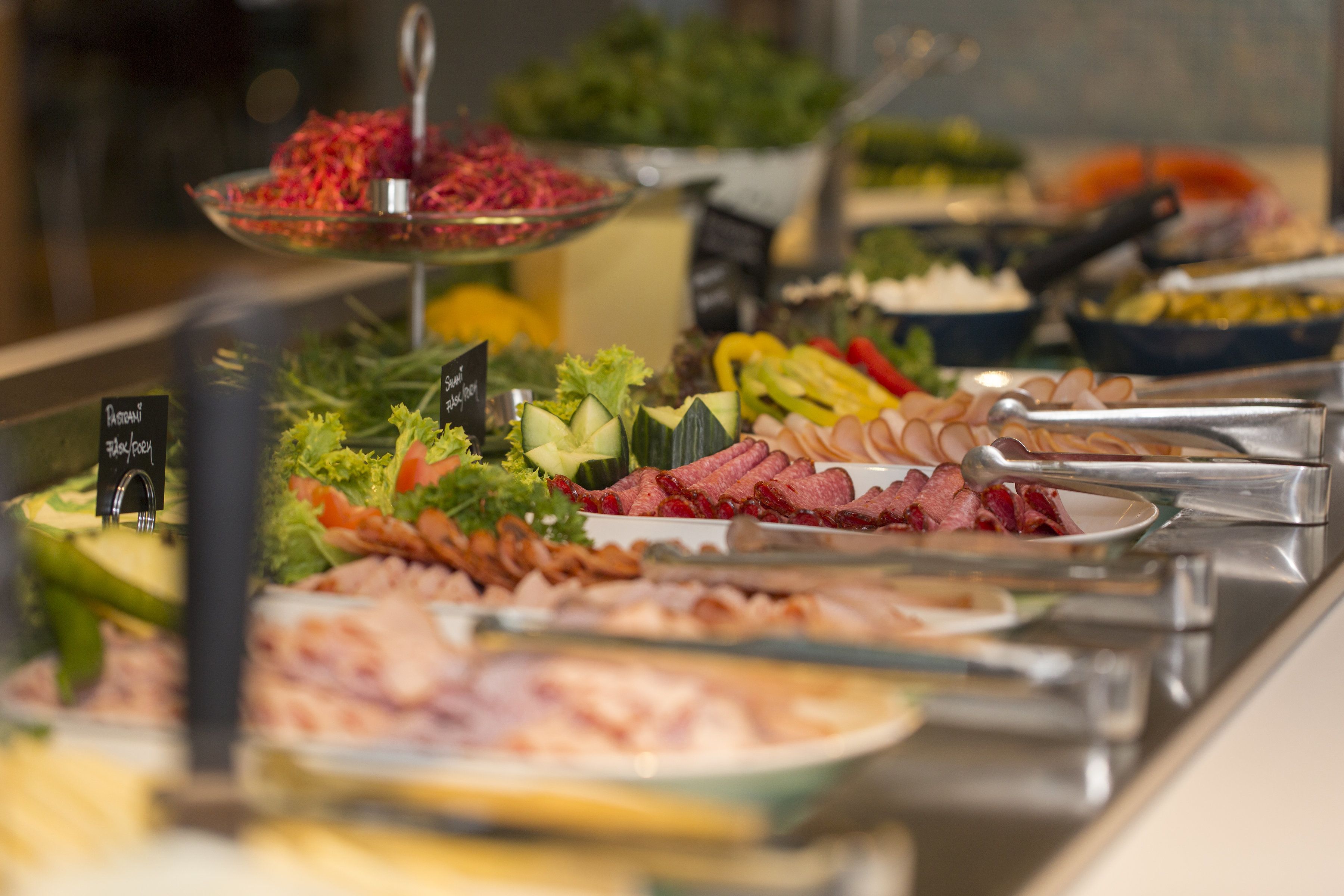 Un bufé con diversas opciones de comida, incluyendo ensaladas, carnes y verduras.