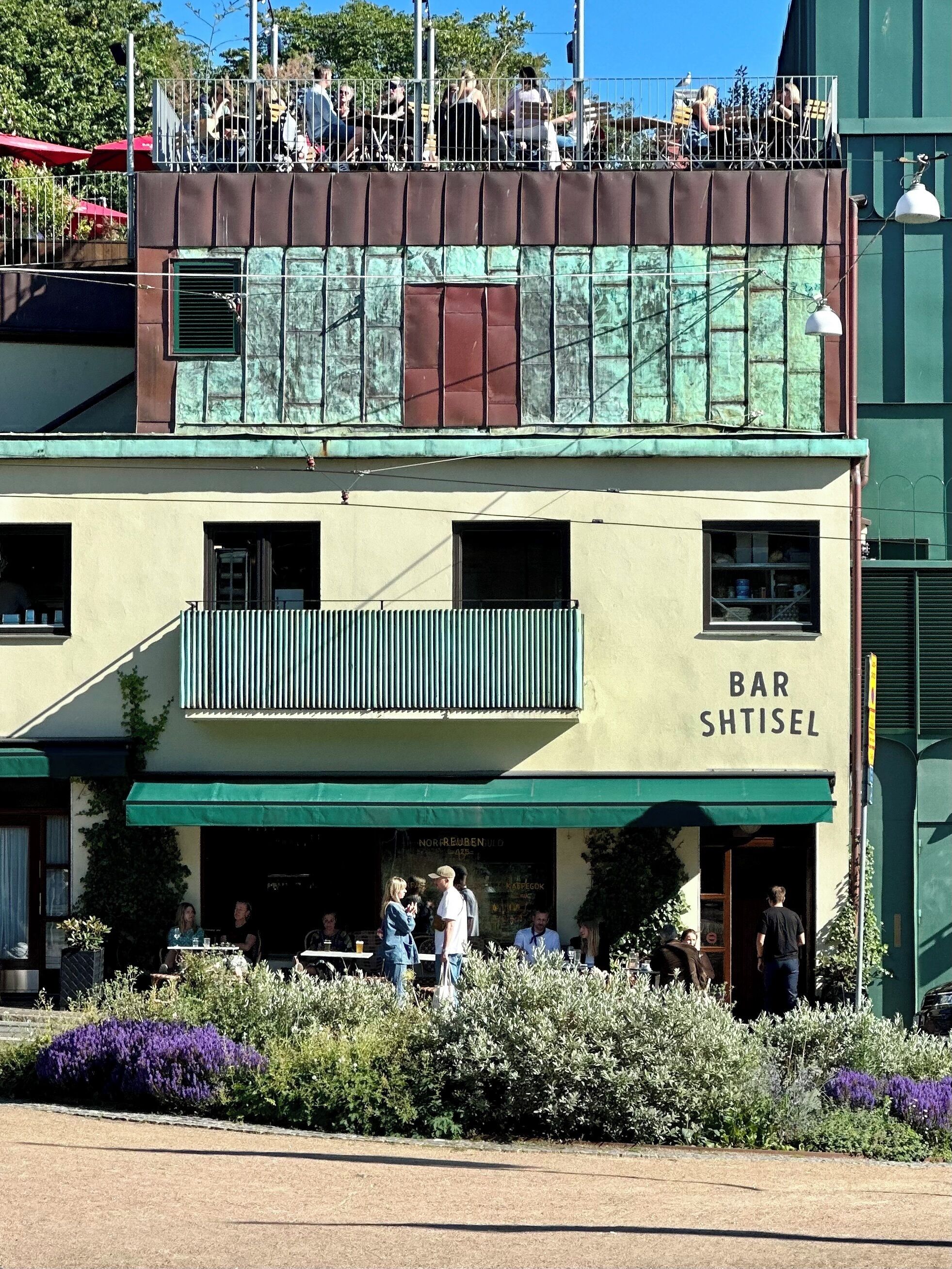 A two-story building with a bar named 'BAR SHTISEL' on the ground floor.