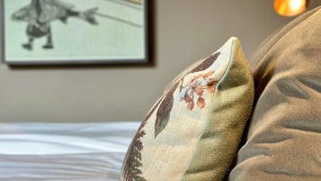 A bed with pillows and a framed picture on the wall.