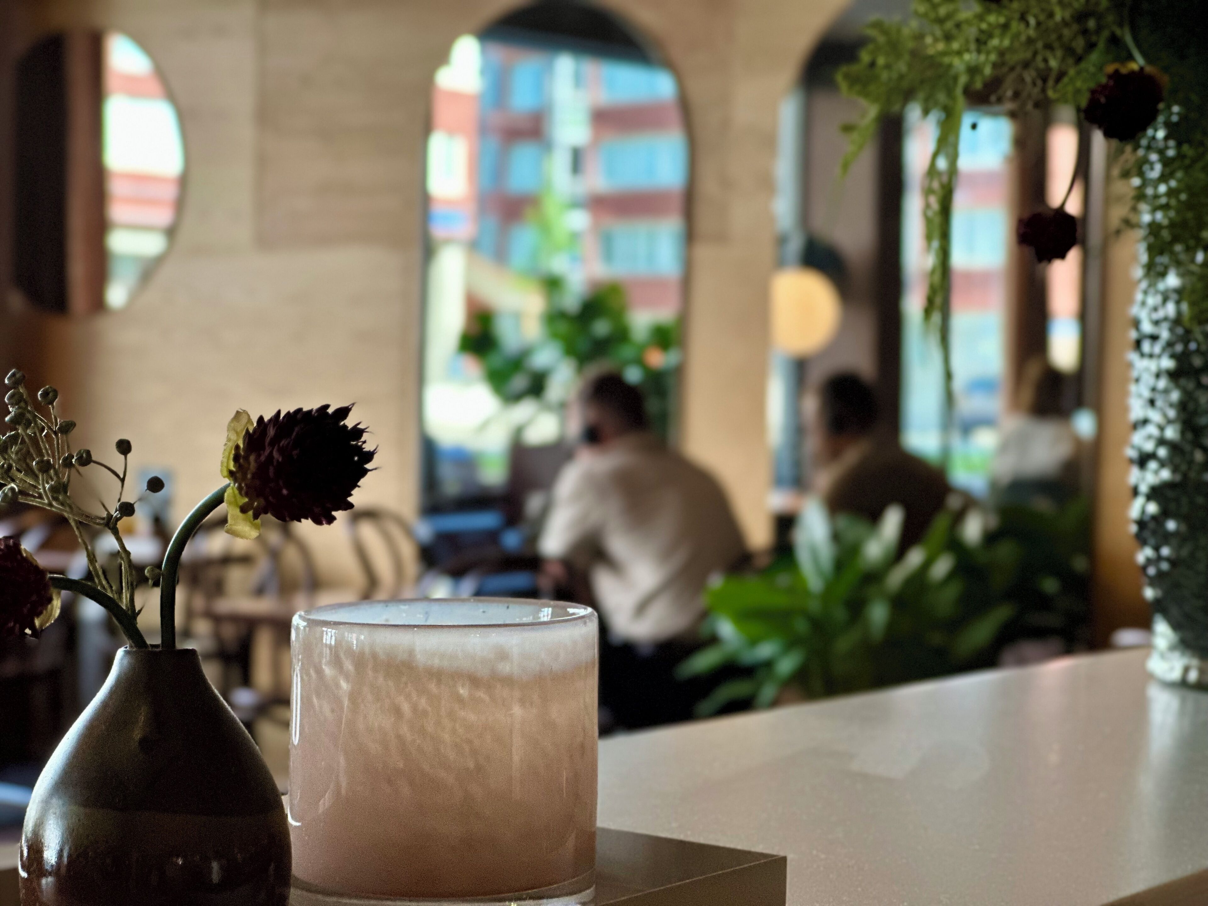 A bar area with a candle, a vase with flowers, and a view of the street outside.