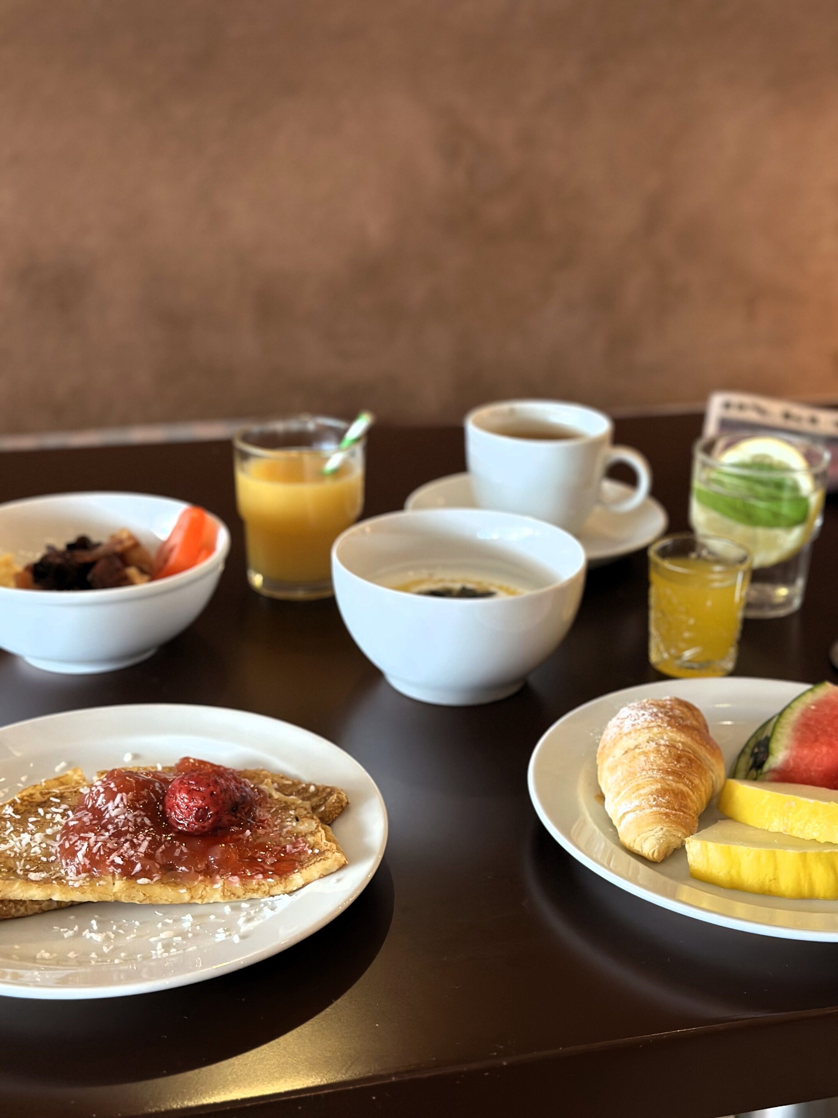 A table with breakfast items including croissants, fruit, and beverages.