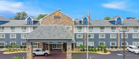 A Comfort Inn hotel with a stone facade, multiple windows, and a parking lot with a white car.