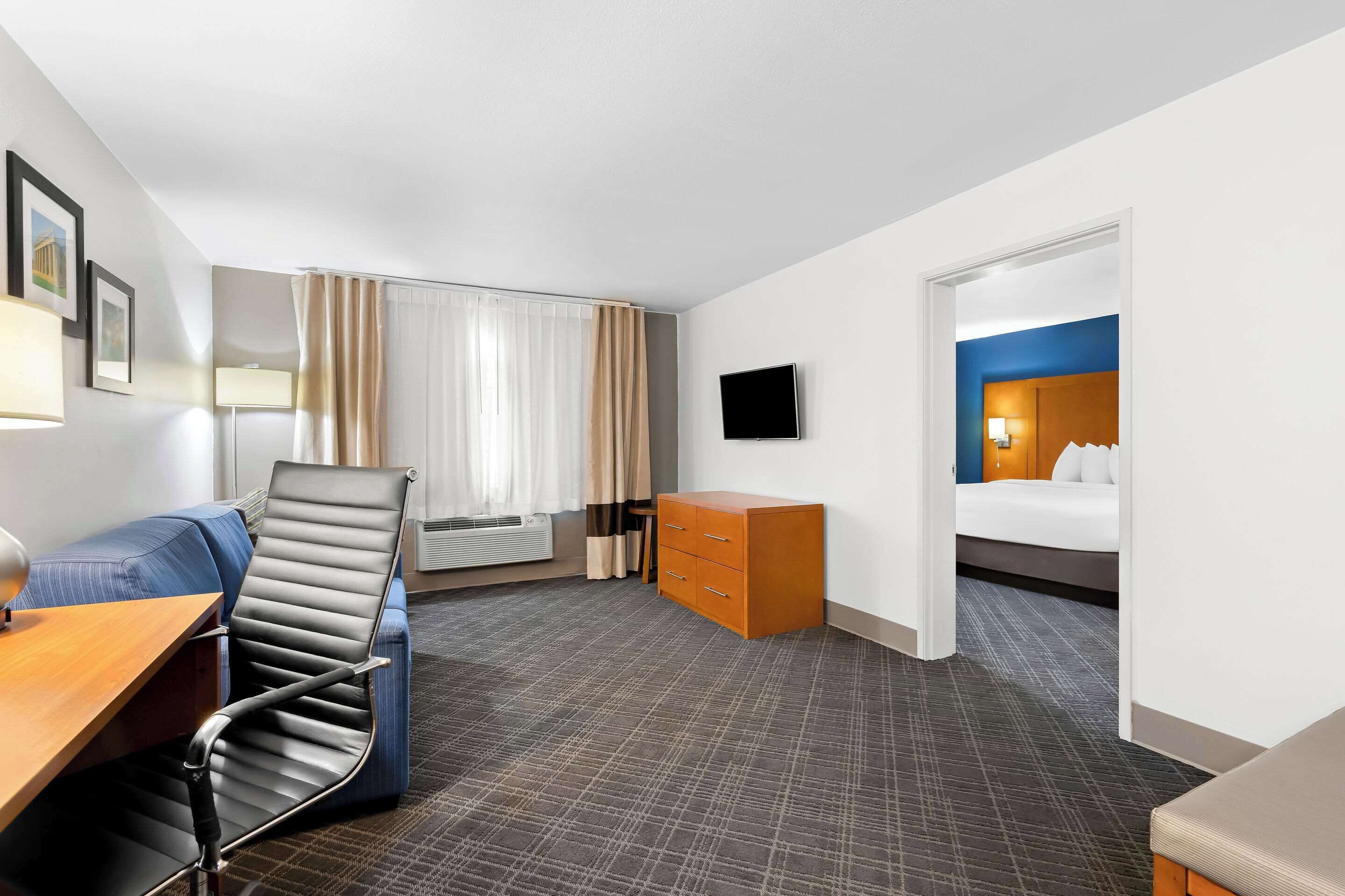 Ein Hotelzimmer mit Schreibtisch, Stuhl, Bett, Schminktisch und Fernseher.