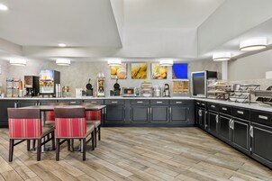 Una cocina moderna con una isla central, asientos tipo bar y diversos electrodomésticos.