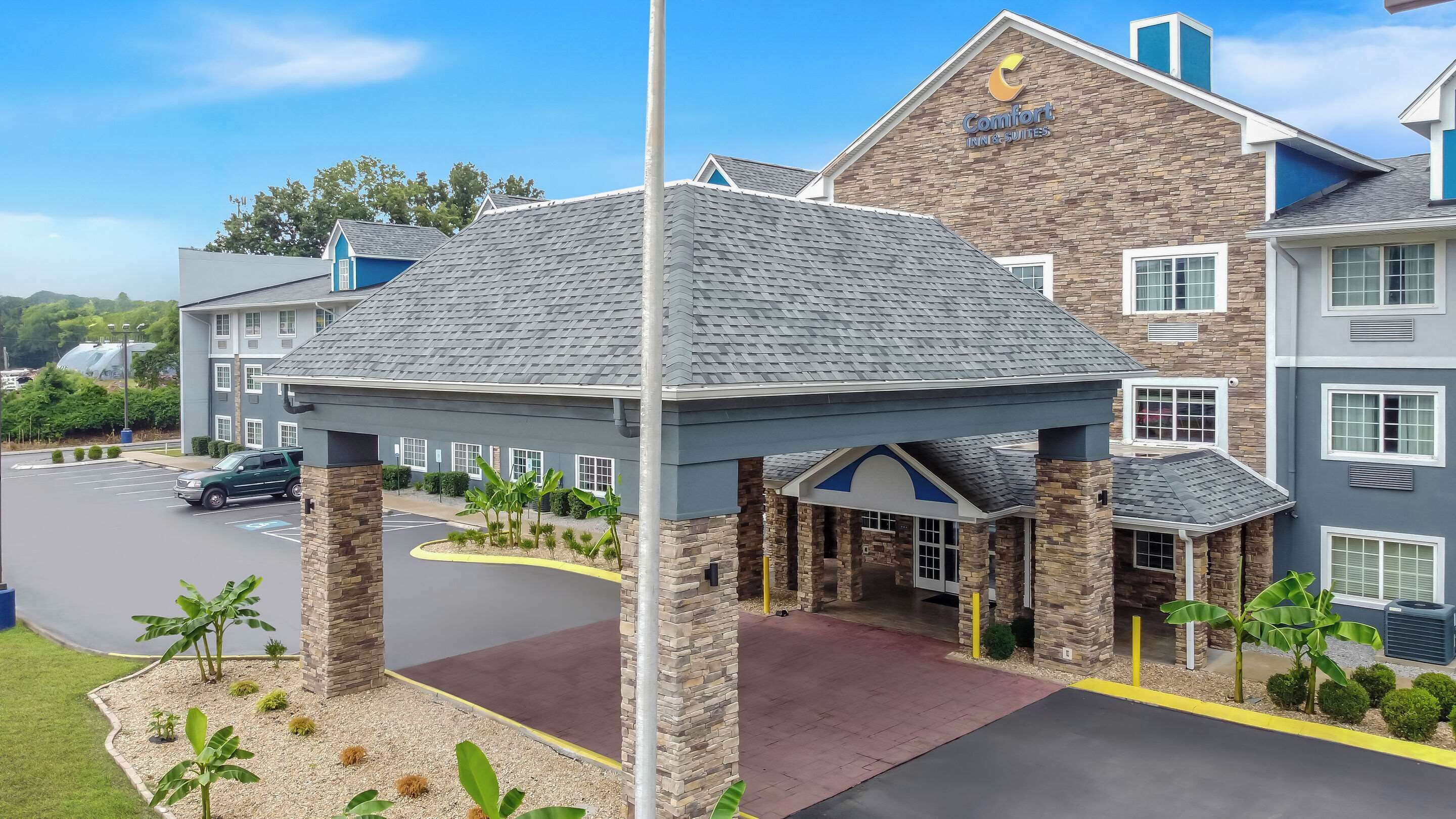 A Comfort Inn & Suites with a covered entrance, stone pillars, and a parking lot.