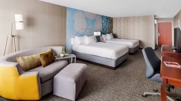 A hotel room with a large bed, a sofa, a desk, and a TV.