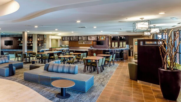A modern lounge area with seating arrangements, a bar, and a menu display.