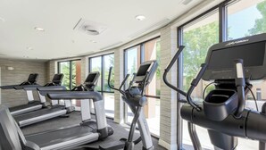 A gym with treadmills and elliptical machines, large windows, and a modern design.